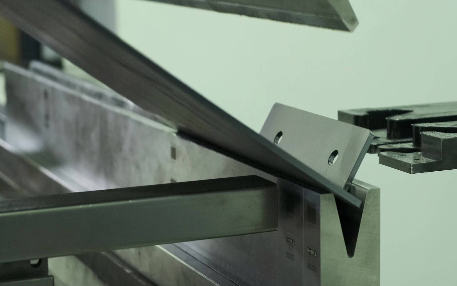 Sheet metal being brake-formed into an L-bracket profile