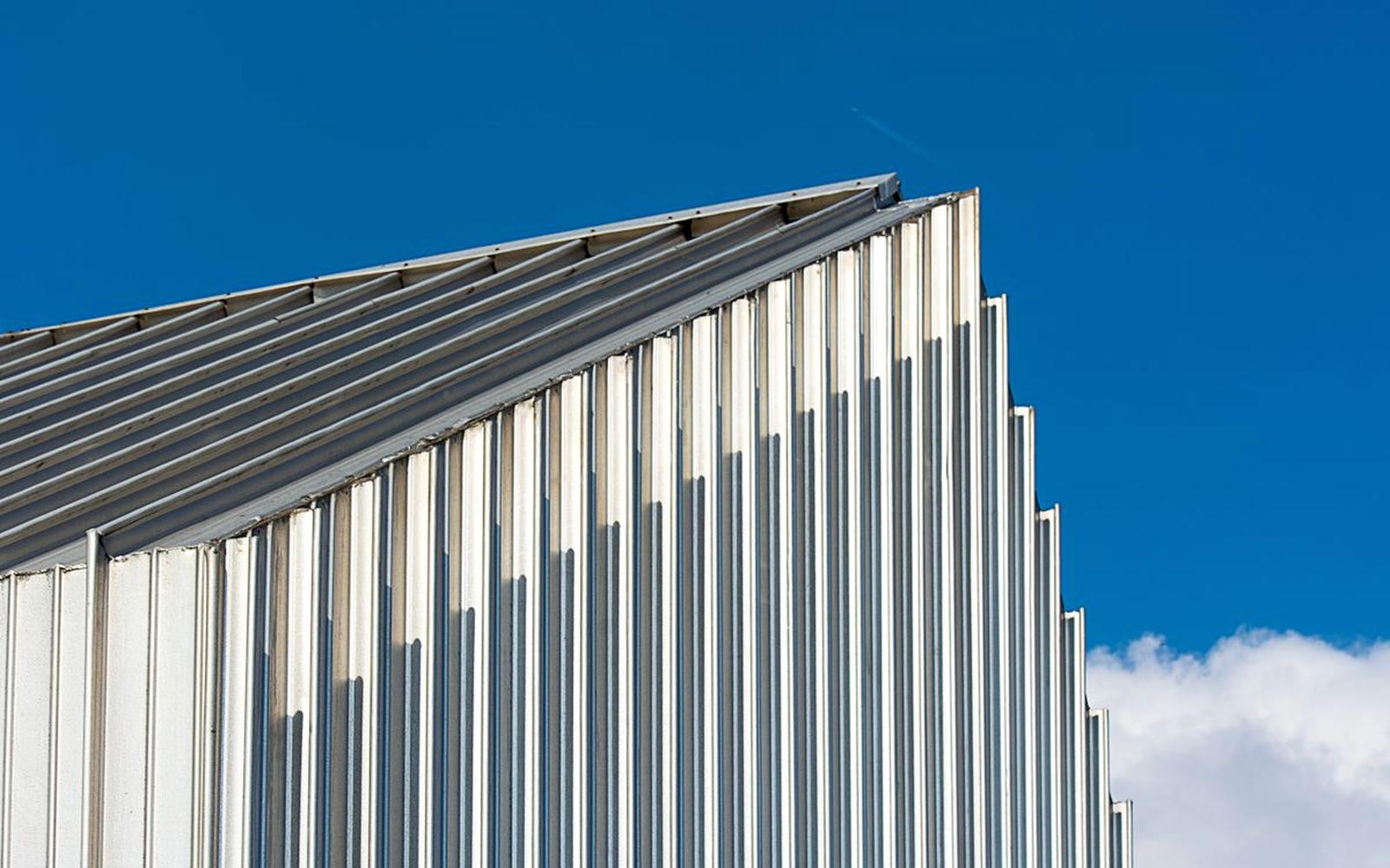 Diagonal ridge line of a corrugated metal roof against a deep blue sky